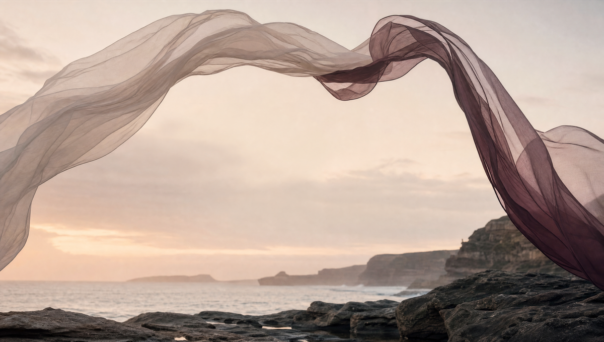 Sheer oatmeal and burgundy fabric floating in the wind above a rocky Sydney coastline at dawn